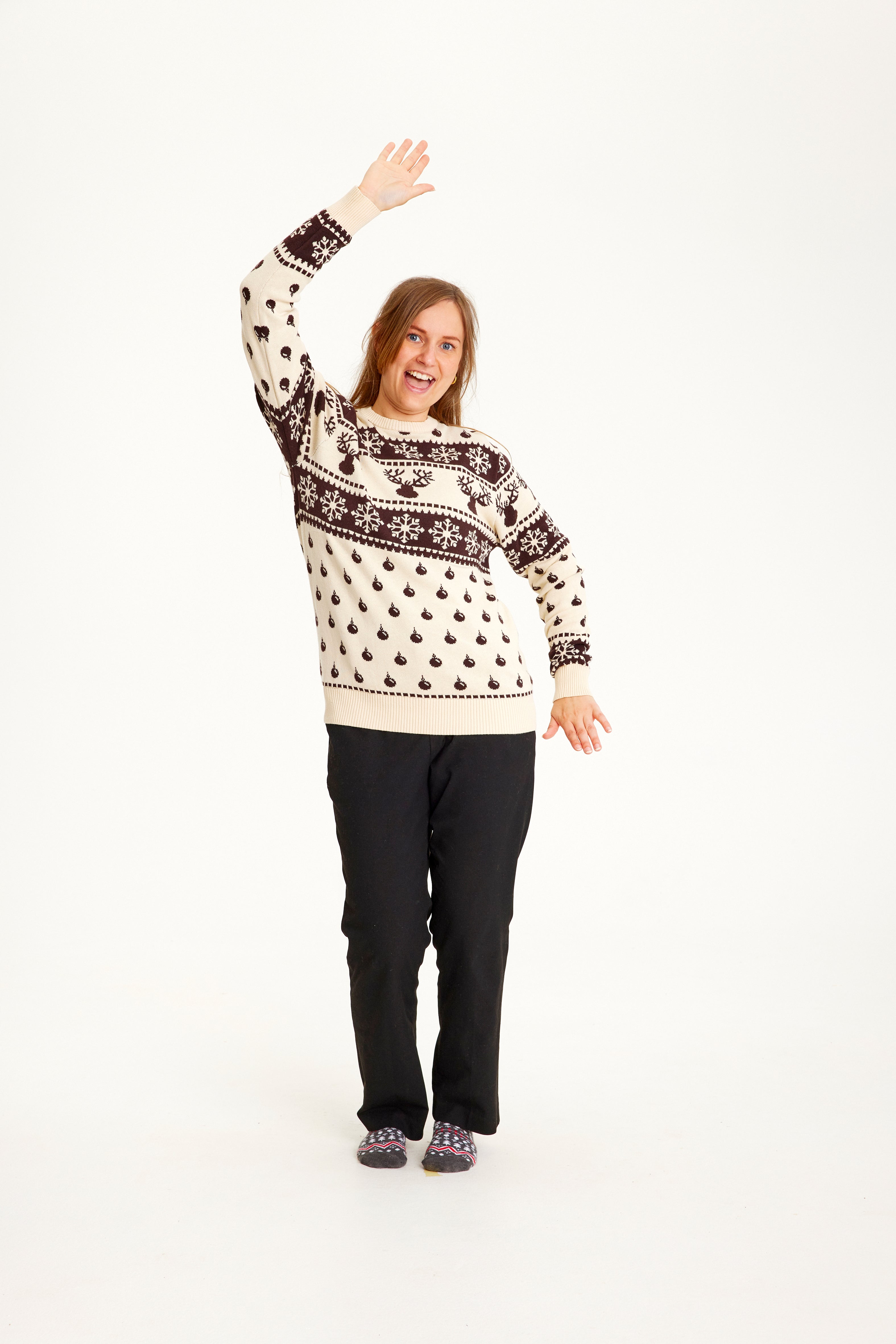 Une femme portant un pull de Noël beige et marron avec des flocons de neige et un motif.